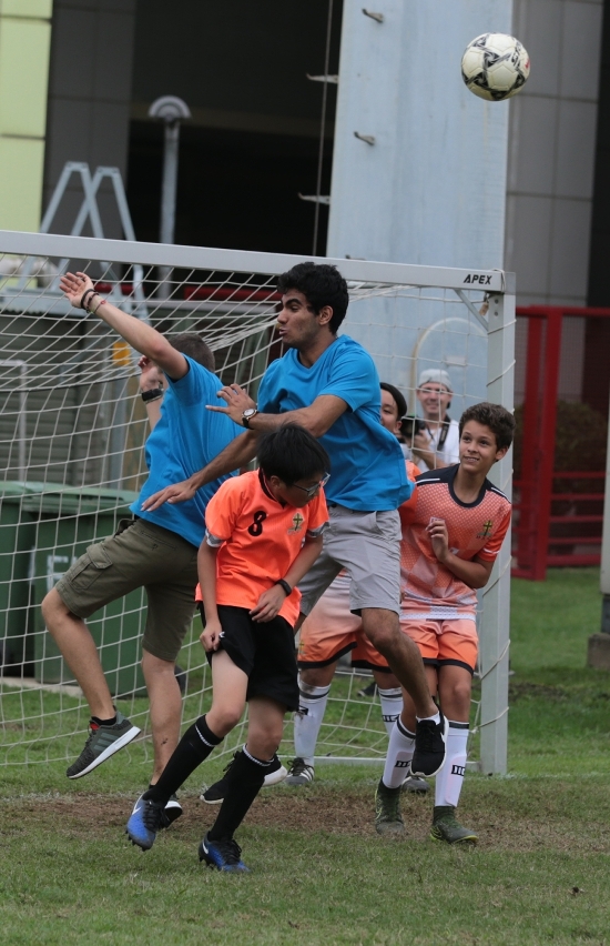 Pilotos e estudantes divertem-se a jogar à bola.