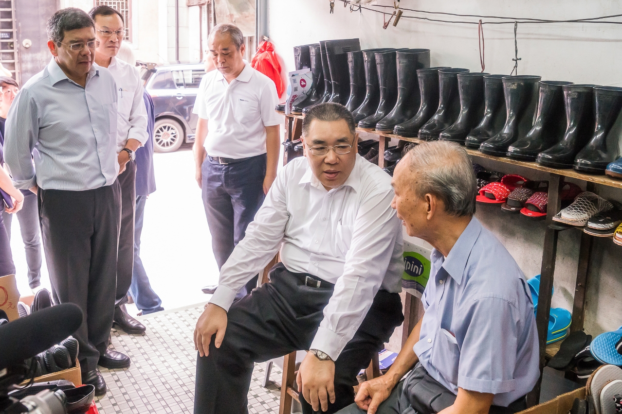 The Chief Executive, Mr Chui Sai On, chats with an owner of a shoe shop near Rua Cinco de Outubro, explaining the Government
