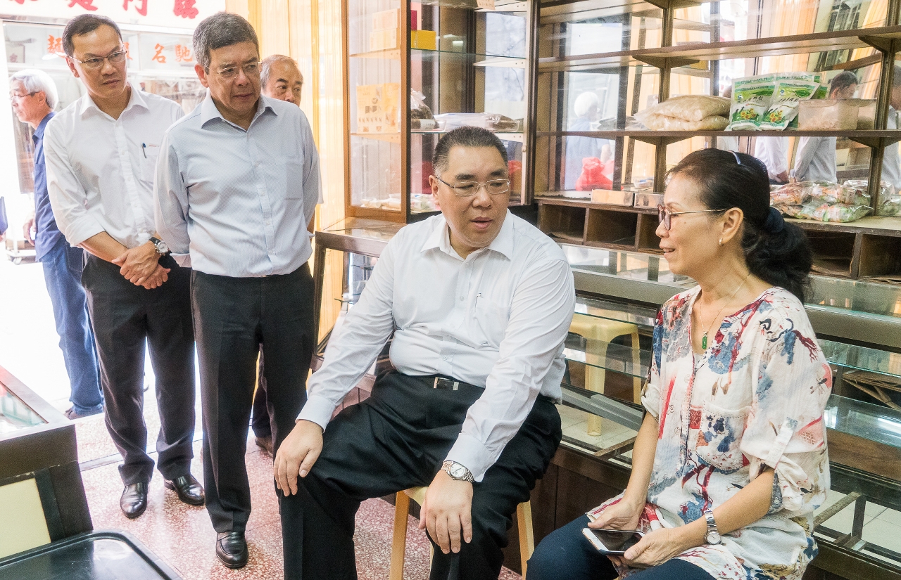 The Chief Executive, Mr Chui Sai On, chats with an owner of a shop selling dried seafood near Rua Cinco de Outubro to gain a better understanding of the impact that the typhoon had on local businesses.