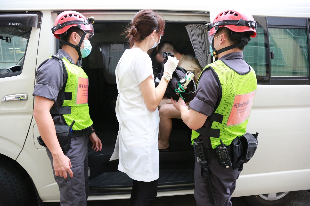 A subida do recluso simulado de ferido à ambulância sob o acompanhamento do pessoal de enfermagem da prisão