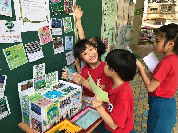 Os vencedores do primeiro lugar da categoria de jardins de infância e ensino primário usam cartas para motivar outros alunos a aprender informações sobre o ambiente.