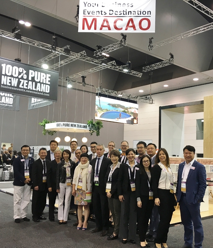 Fotografia de grupo dos representantes do IPIM e dos operadores da indústria de convenções, exposições e turismo, em frente do “Pavilhão de Macau” instalado no AIME 2017