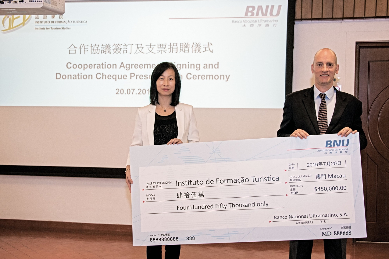 Mr. Pedro Cardoso, Chief Executive Officer of BNU passes the scholarship cheque to IFT President, Dr. Fanny Vong.