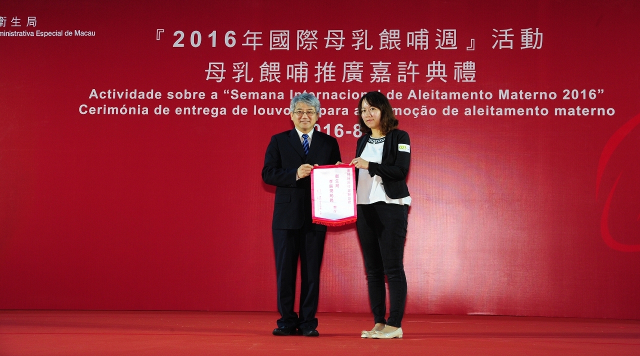 O Director dos Serviços de Saúde, Dr. Lei Chin Ion recebe a bandeira de sede atribuída pela Presidente da Associação de Amamentação de Macau