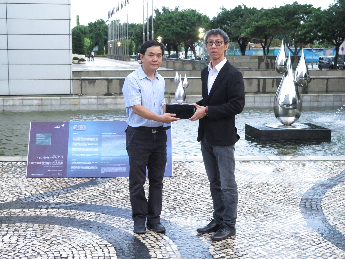 O presidente da Associação de Escultura de Macau, Ng Sang Kei, distribui o modelo da escultura para o director do Museu de Arte de Macau, Chan Hou Seng