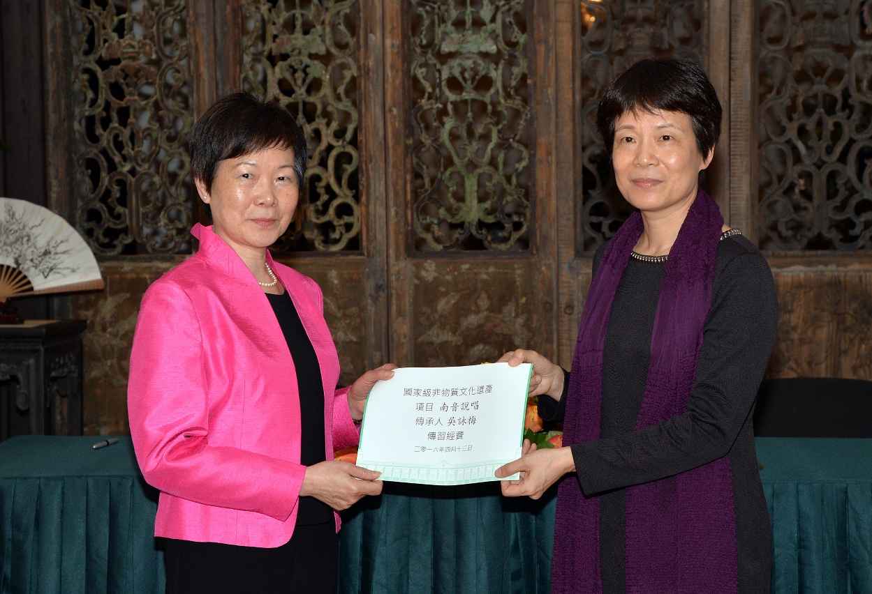 A Directora do Departamento de Cultura e Educação do Gabinete de Ligação do Governo Popular Central na R.A.E. de Macau, Xu Ting (à direita) distribuiu verbas à herdeira representativa do “Património Cultural Intangível” a Nível Nacional －Naamyam Cantoneses, Ng Wing Mui, que foi representada por uma familiar, Choi Pui Lin (à esquerda).