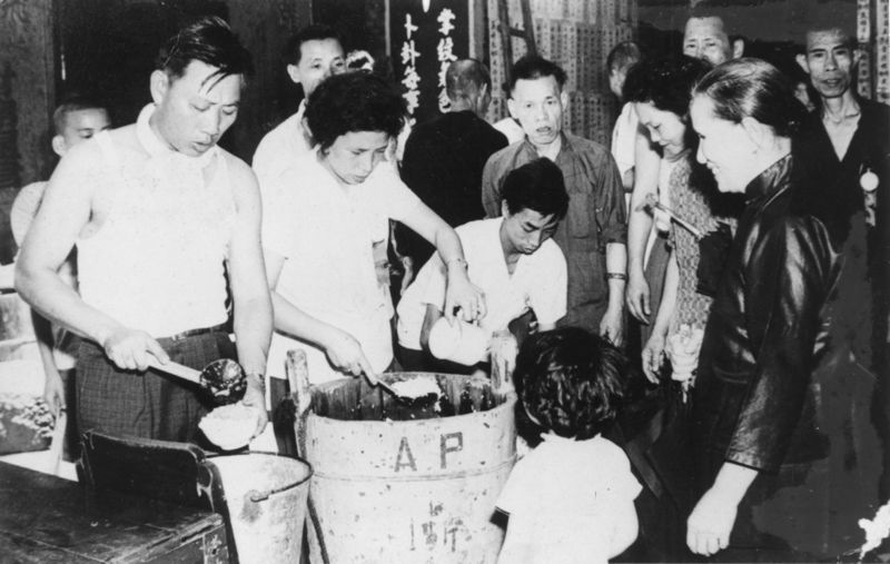 60年代初市民自攜器皿到營地街市三街會館前地領取龍船頭飯的情況（相片由澳門鮮魚行總會張國柱副會長提供）