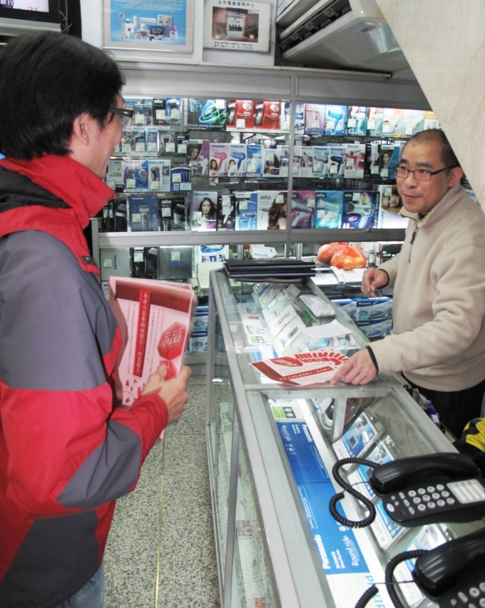 Distribuição pelo pessoal da DSSOPT aos comerciantes do panfleto informativo sobre a interrupção antecipada durante a quadra festiva do ano novo lunar da obra de reordenamento da rede de drenagem da Avenida de Horta e Costa.