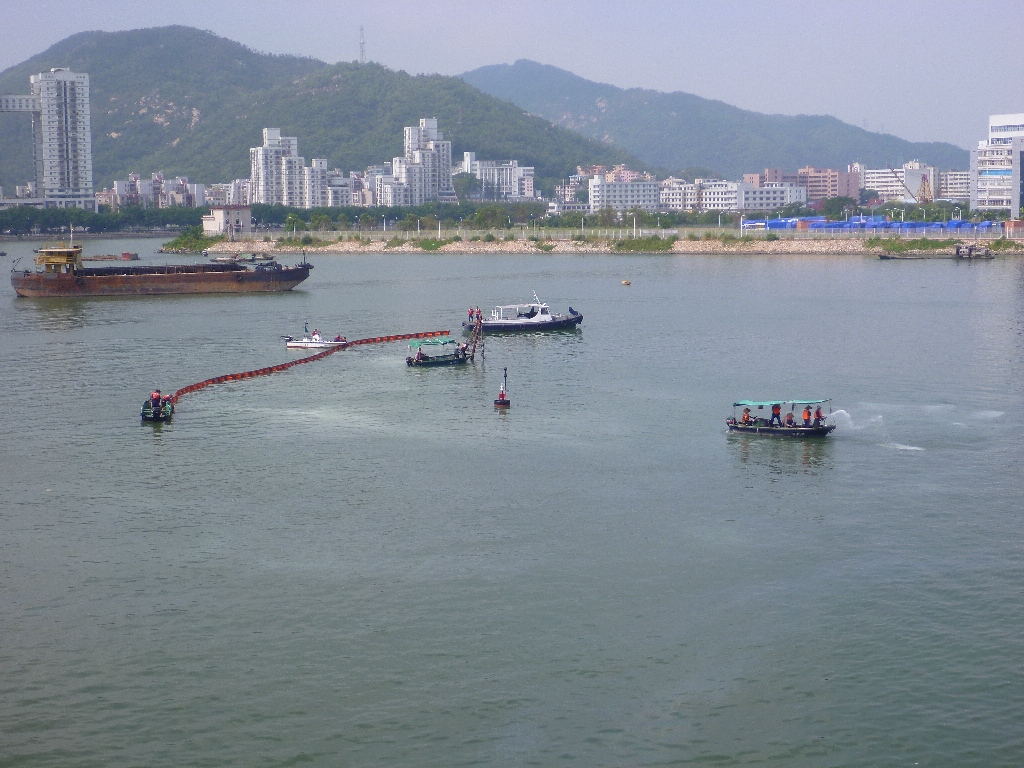 港務局船隻在海面投放化油劑和設置圍油欄