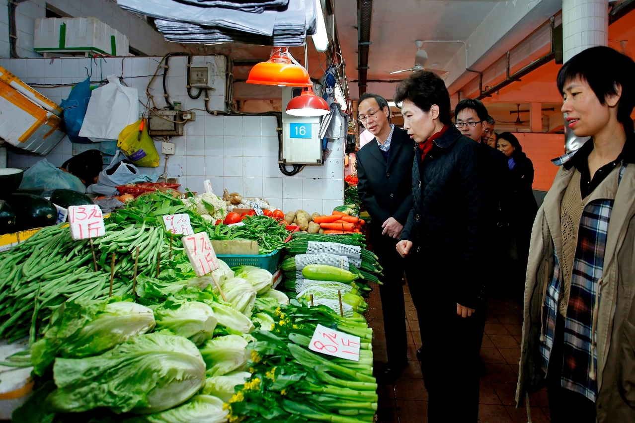 Visita da Vice-Ministra do Comércio, Gao Yan, ao mercado de Iao Hong para inteirar-se da situação de abastecimento dos produtos agrícolas e derivados, na companhia do Presidente subst. do Conselho de Administração do IACM, Lo Veng Tak.