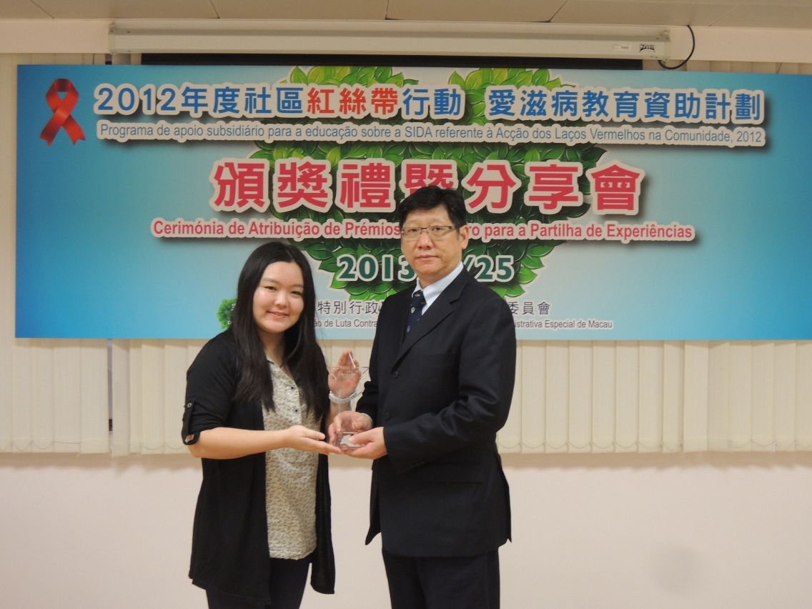 O Director dos Serviços de Saúde, substituto, Dr. Chan Wai Sin, atribui o prémio de laços vermelhos ao premiado “Centro de Serviços Comunitários da Areia Preta da União Geral das Associações dos Moradores”.